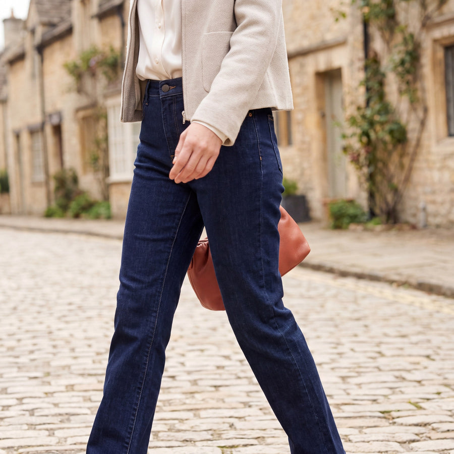 Woman styling dark jeans on a Cotswolds village street