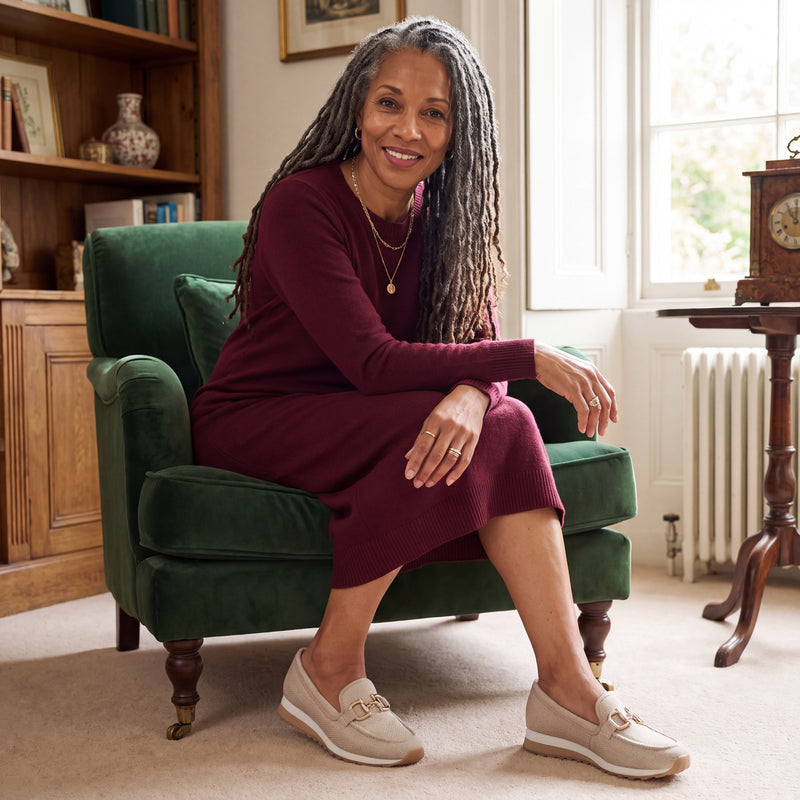 Woman with salt-and-pepper locs wearing beige woven Lili loafers in a refined living room