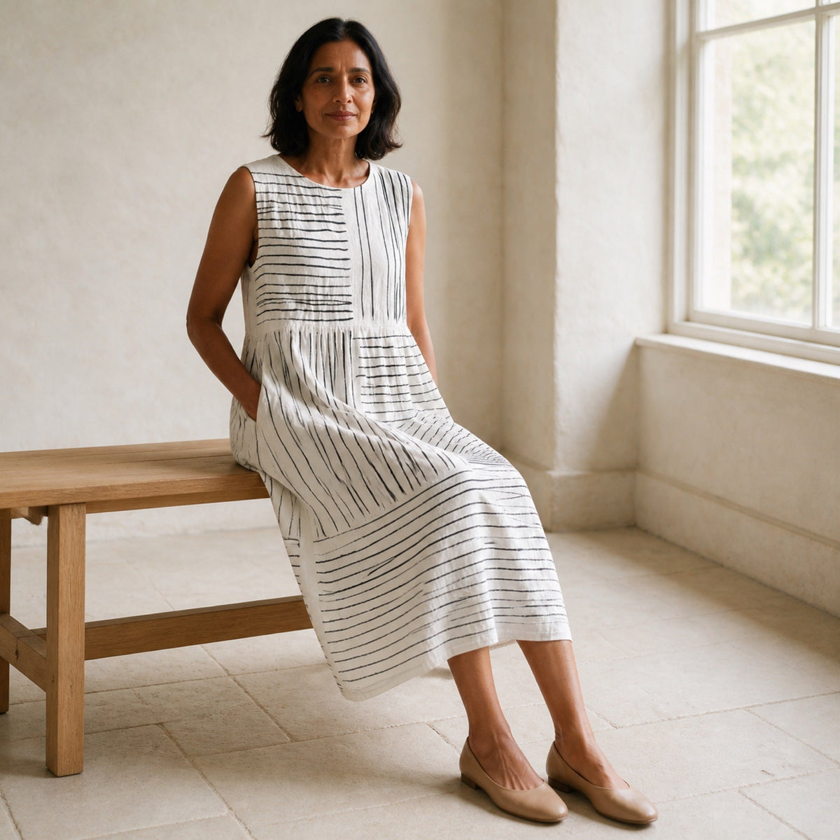The Amara midi dress styled seated in a warm neutral studio