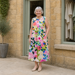 Margaret wearing the multicolour Ava Floral Midi Dress, contextual full-body view outside the Cotswold stone boutique.