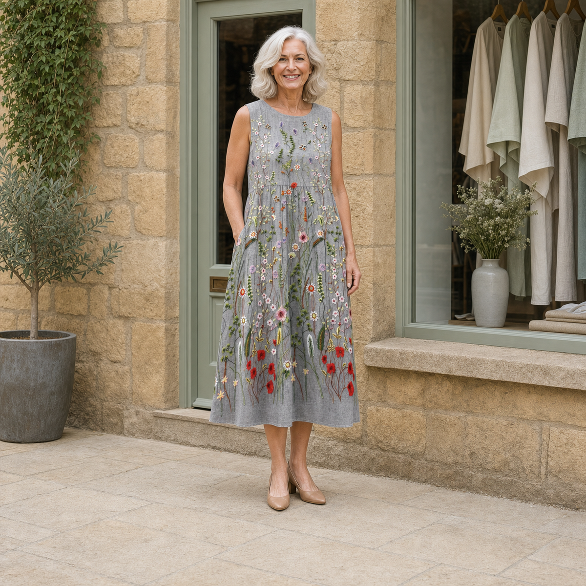 Rose wearing the multicolour Cara Wildflower Midi Dress, contextual full-body view outside the Cotswold stone boutique.