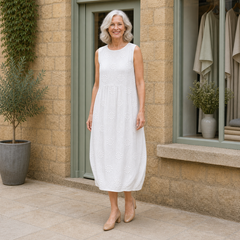 Rose wearing the white Rose Embroidered Midi Dress, three-quarter full-body view outside the Cotswold stone boutique.