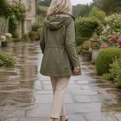 Back view of The Hadley rain jacket in sage in an English garden