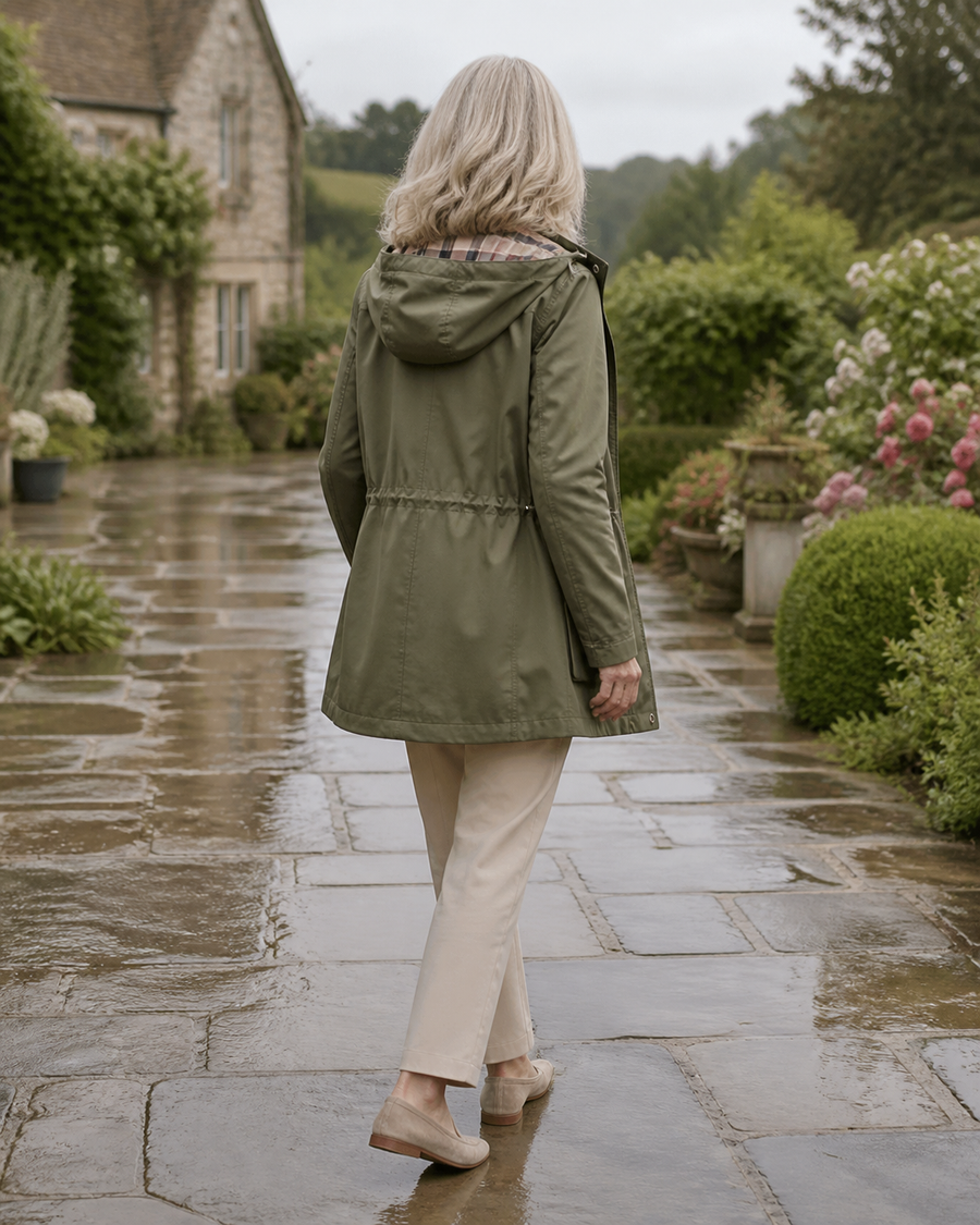 Back view of The Hadley rain jacket in sage in an English garden