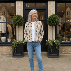 Woman wearing the beige Moxley feline motif knit cardigan outside Cotswold & Rose