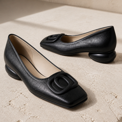 Opium black square-toe flats on Cotswold limestone