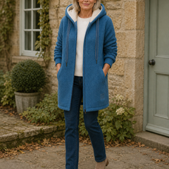 Phoebe blue longline hooded fleece jacket outside an autumn cottage